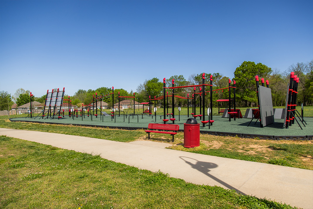 Outdoor fitness area in Farmington park with various exercise stations including pull-up bars, climbing ropes, and balance beams for athletic development